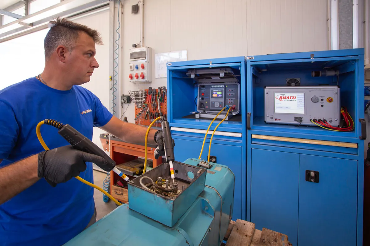 Tecnico accanto al banco prova con quadro elettrico blu